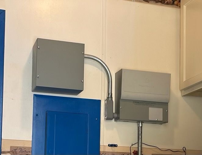 A gray box is hanging on a white wall next to a blue cabinet.