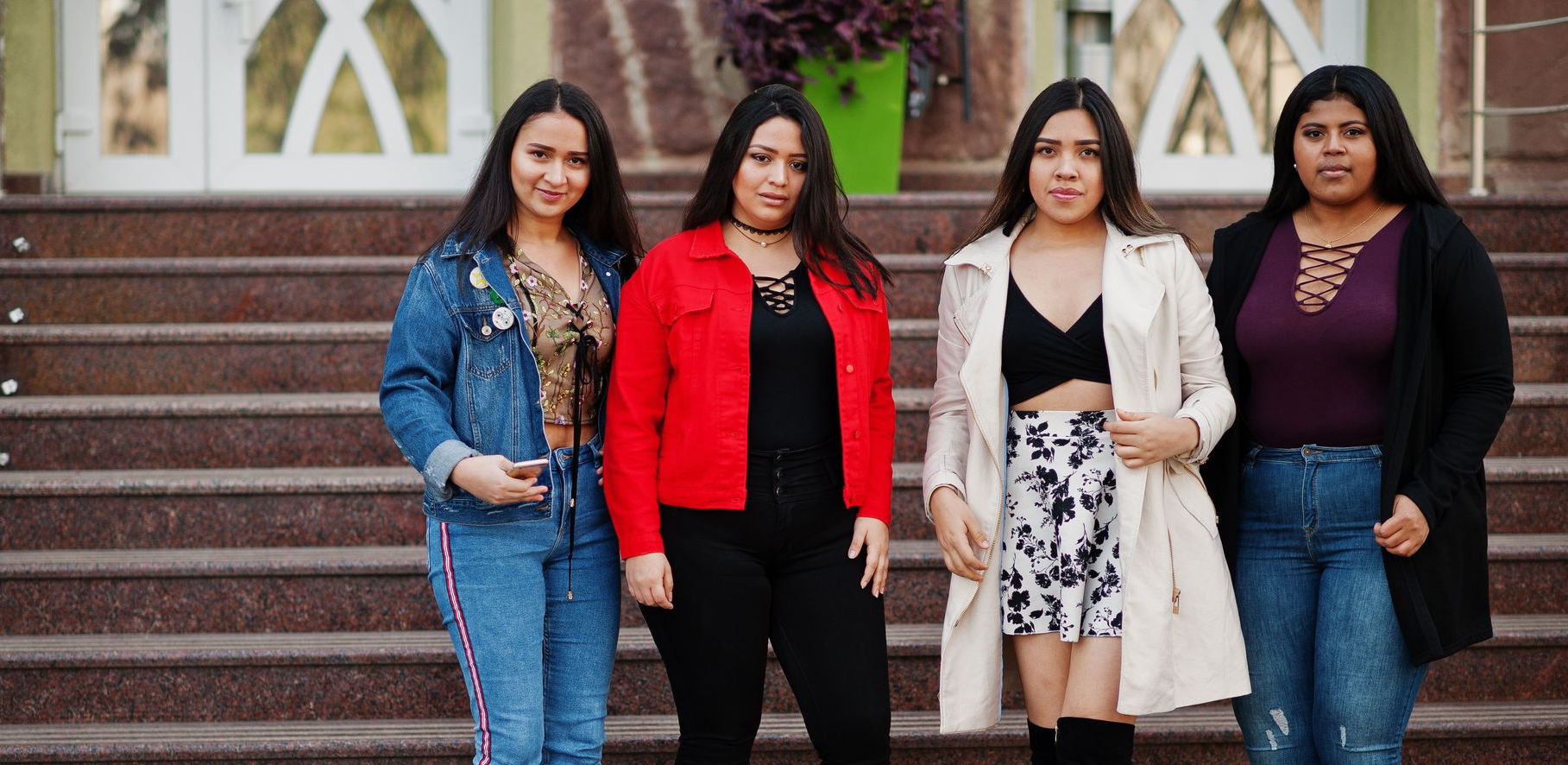 Six people smiling and embracing in a sunlit park.