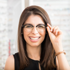 Woman smiling, adjusting glasses. Wearing black and gold glasses, in an eyewear store. Woman smiling, adjusting glasses. Wearing black and gold glasses, in an eyewear store.