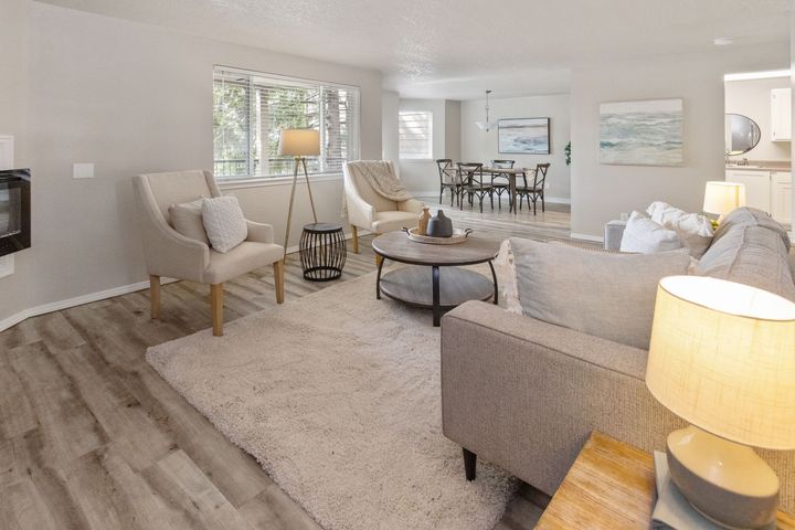Living room with neutral colors: chairs, sofa, round coffee table, rug, and dining area visible.