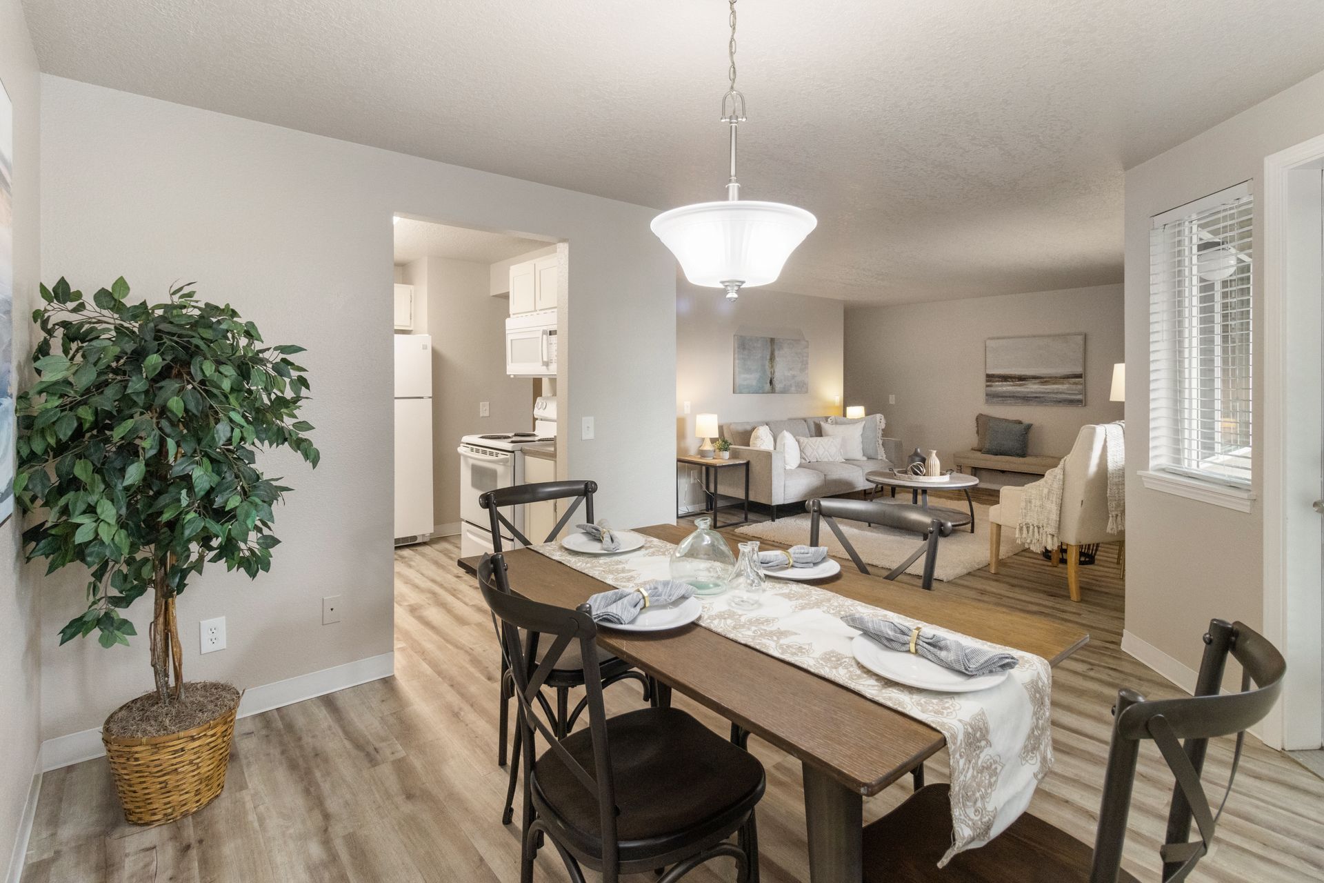 Dining room with a table set for a meal, leading into a living room.