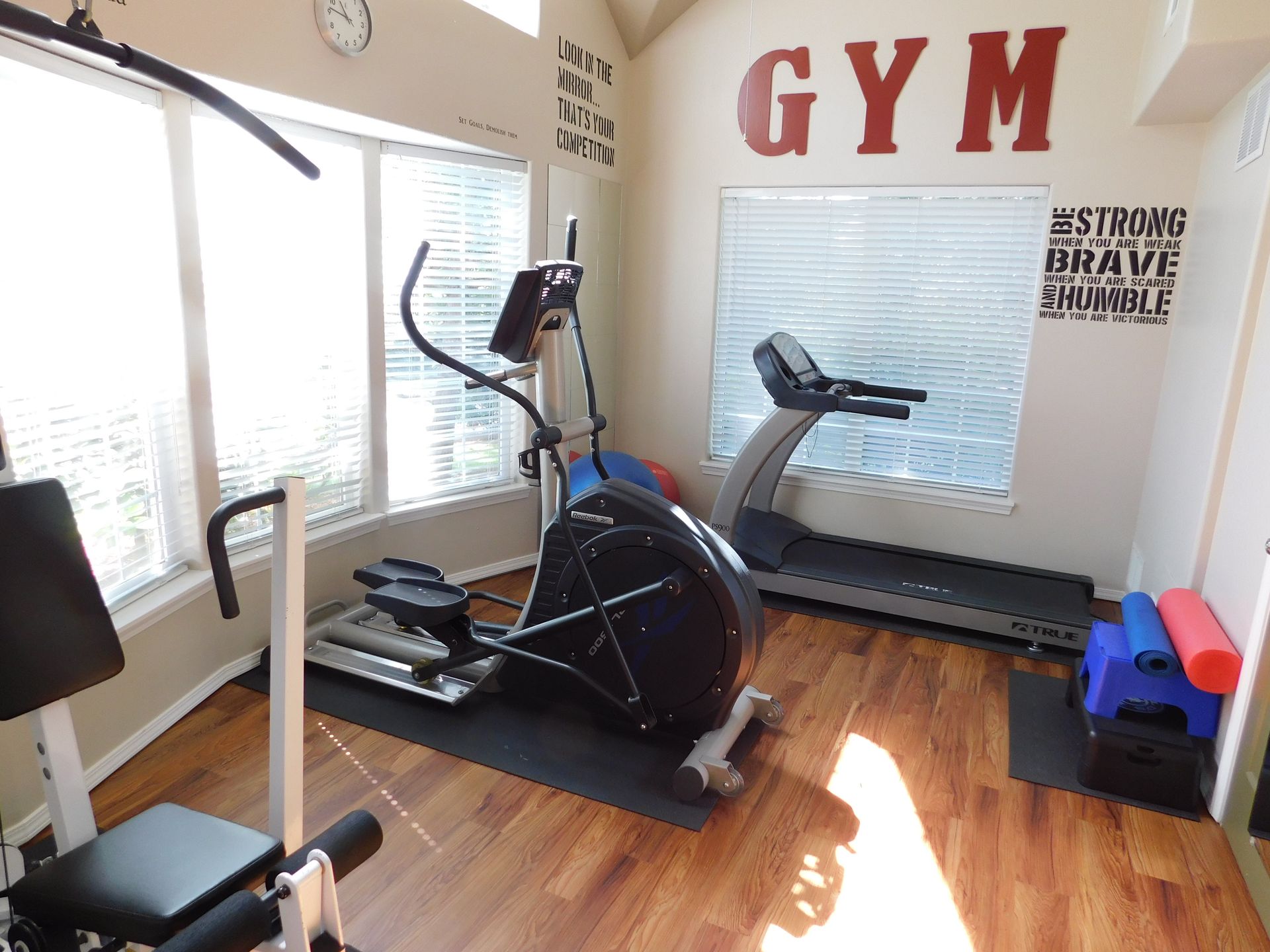 Home gym with elliptical machine, treadmill, and weight equipment. 