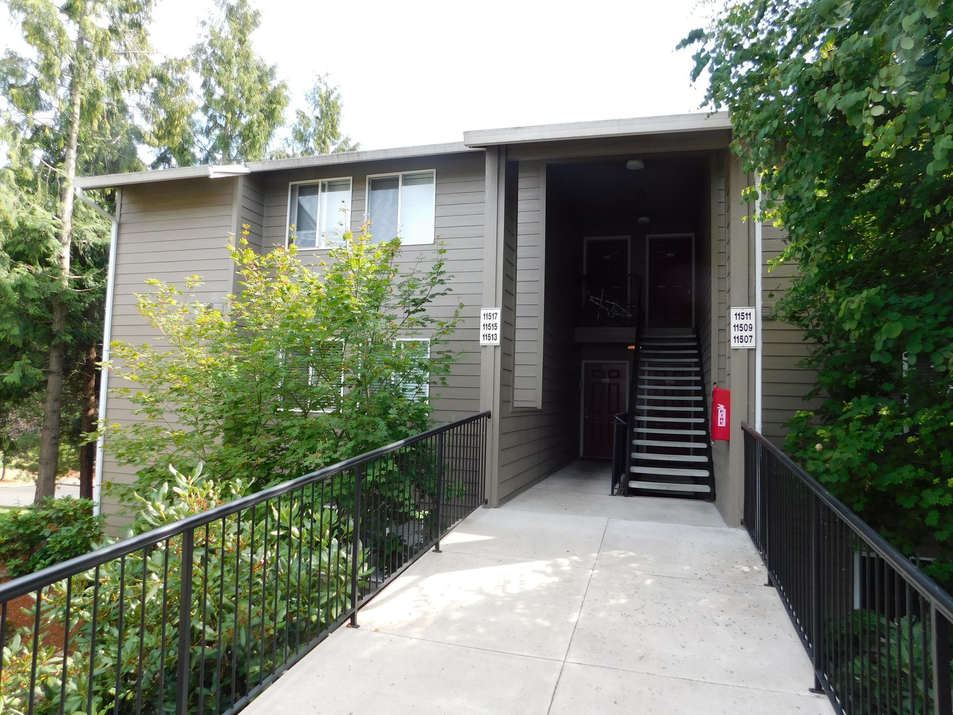 Two-story apartment building entrance with a walkway and stairs.