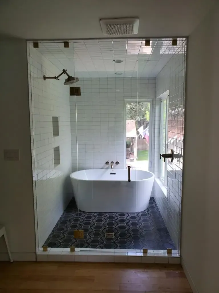 A bathroom with a bathtub and a shower behind a glass door.