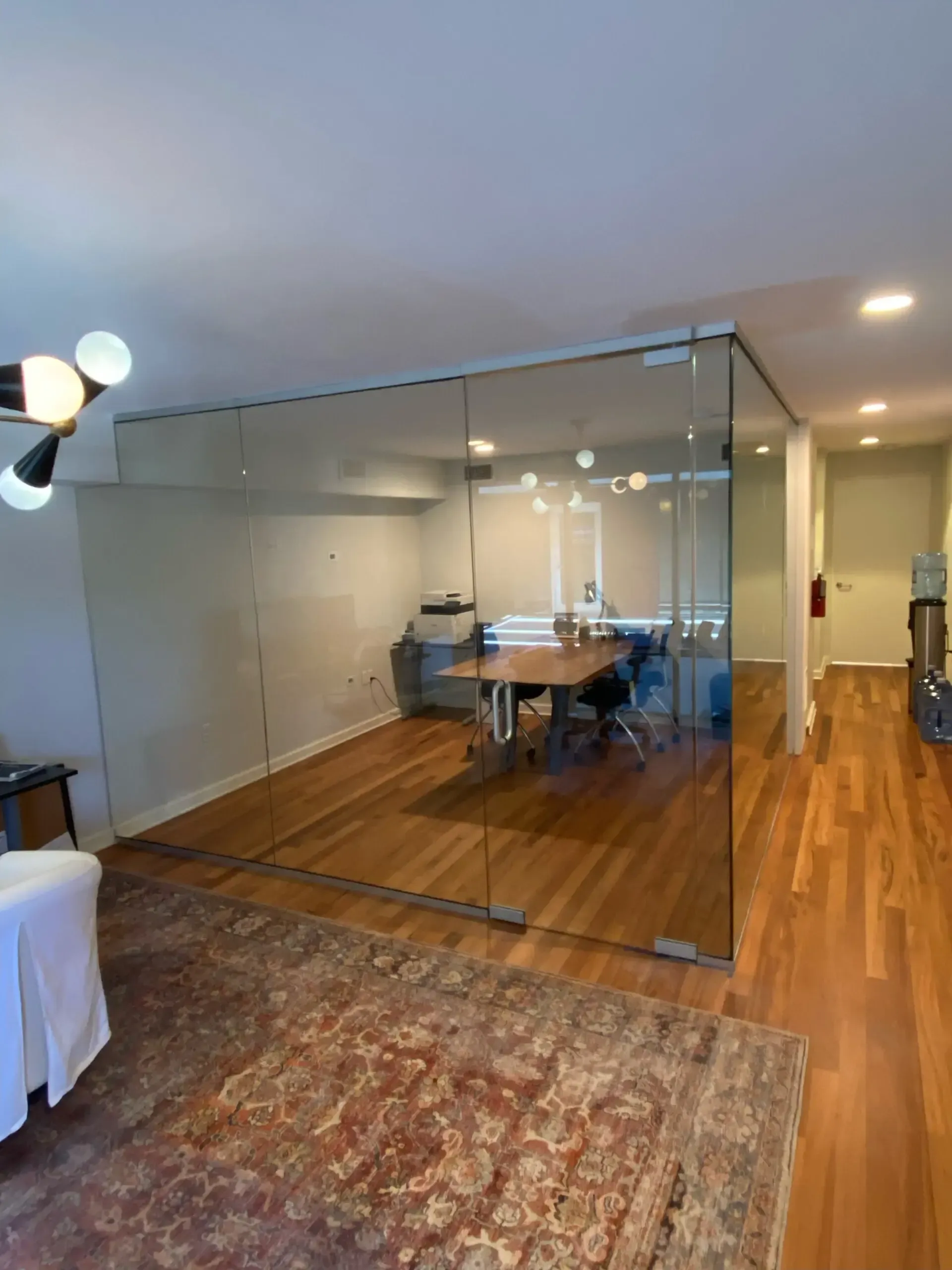 A living room with hardwood floors and a glass wall.