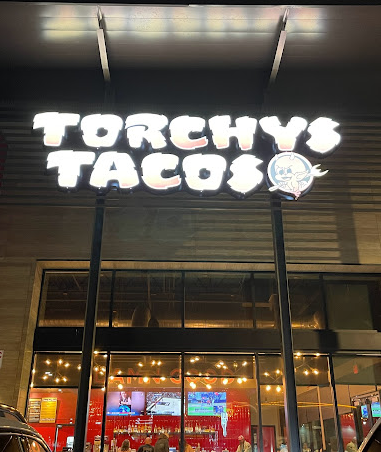 A sign for torchy 's tacos is lit up at night