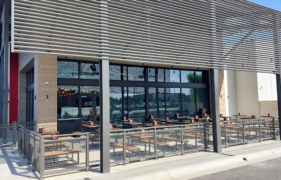 A restaurant with tables and chairs outside of it.