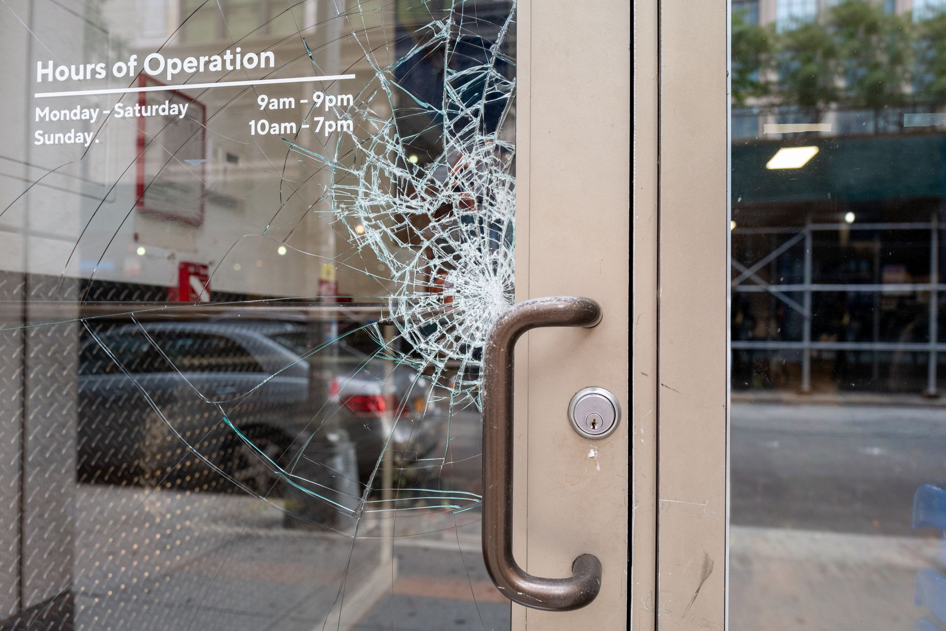 A broken glass door with the words hours of operation written on it.