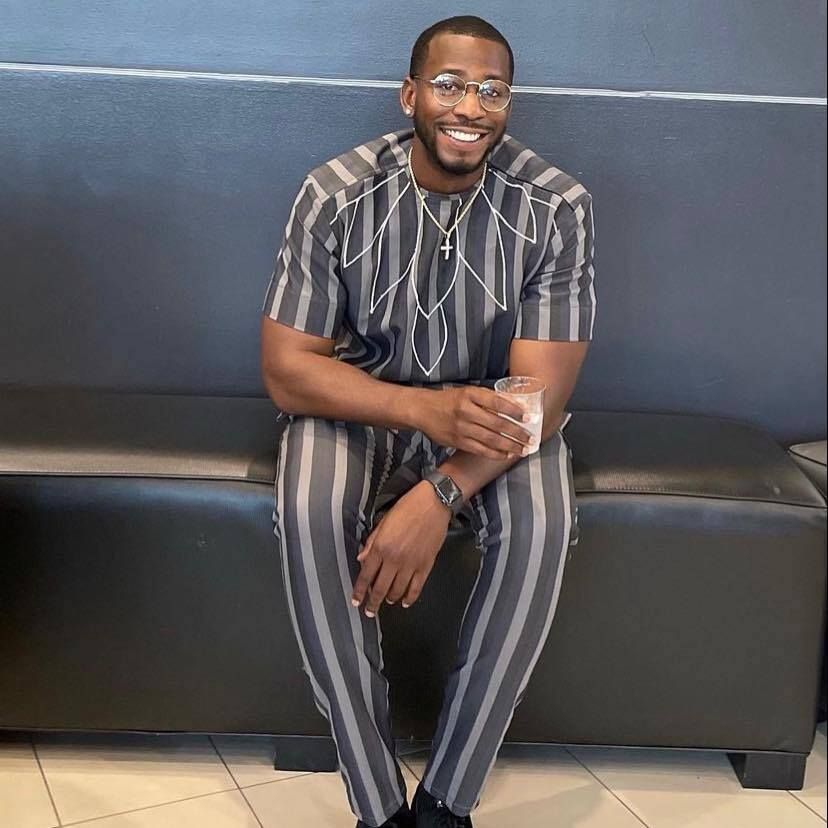 A man in a striped shirt and pants is sitting on a couch.