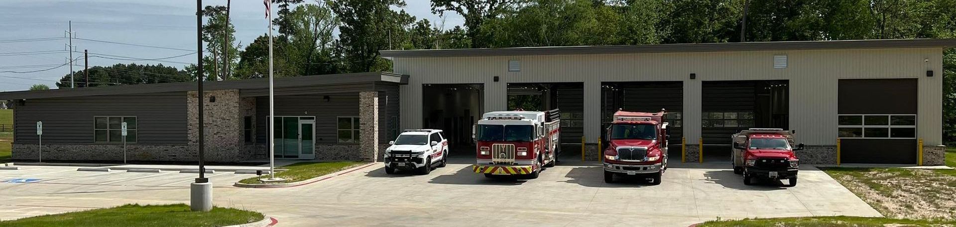 A row of fire trucks are parked in front of a fire station.