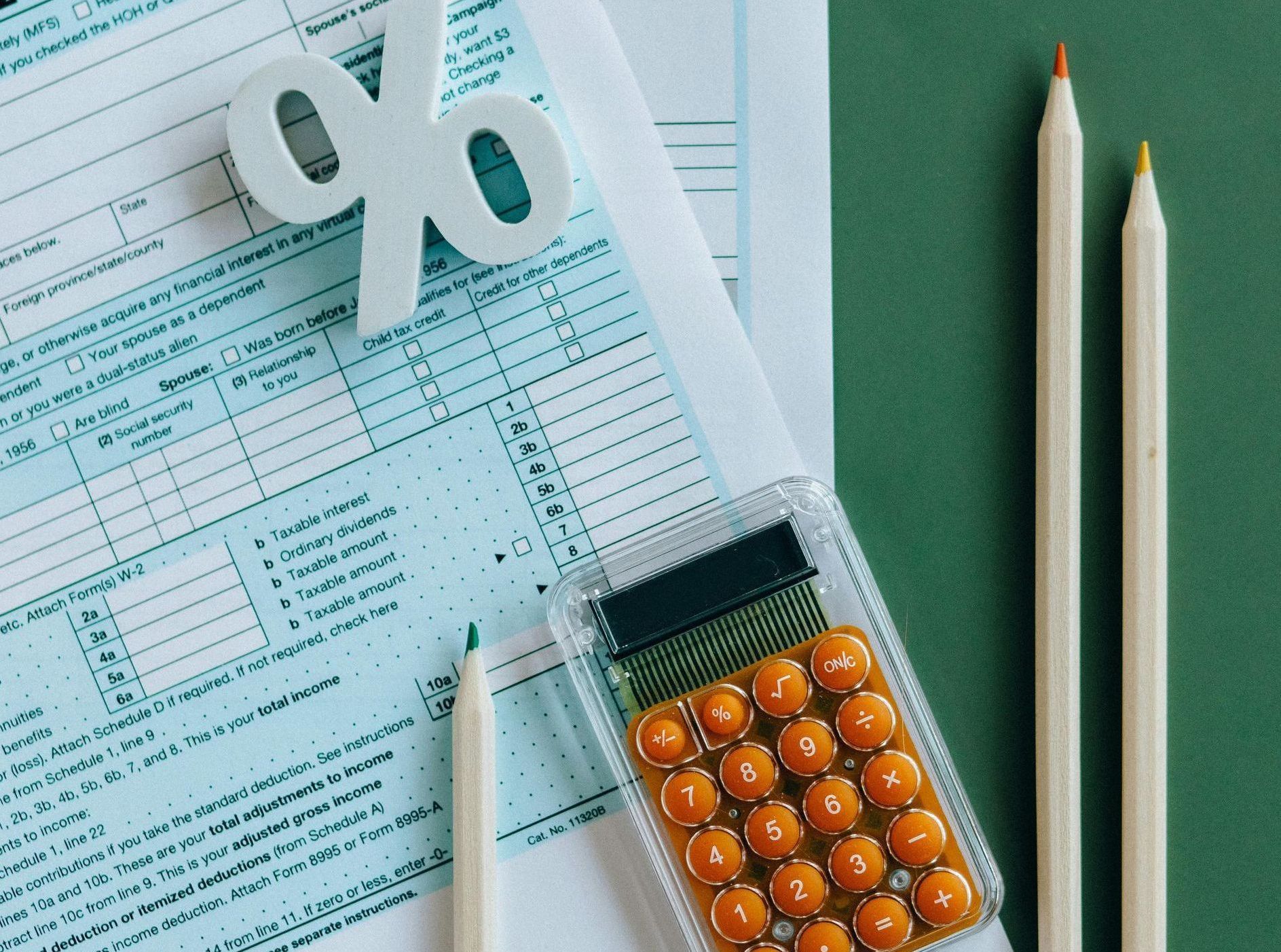 A calculator is sitting on top of a piece of paper next to two pencils.