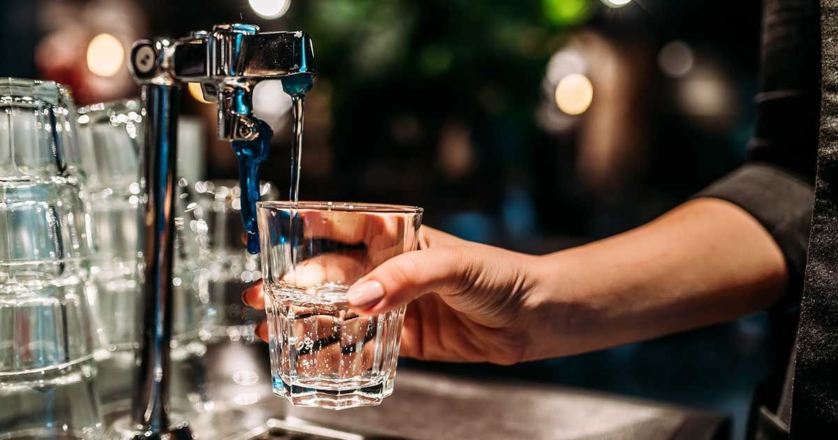 A construction worker wearing a blue hard hat is working on a roof