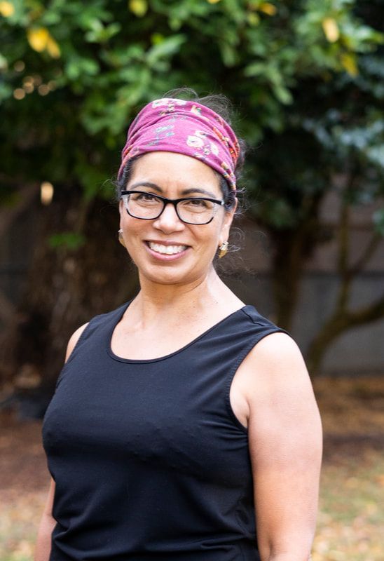 A woman wearing glasses and a headband is smiling for the camera.