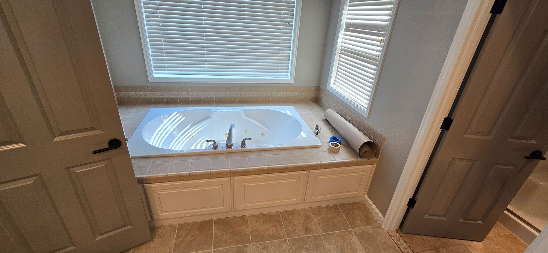 Bathtub set in a tiled alcove with light-colored cabinets