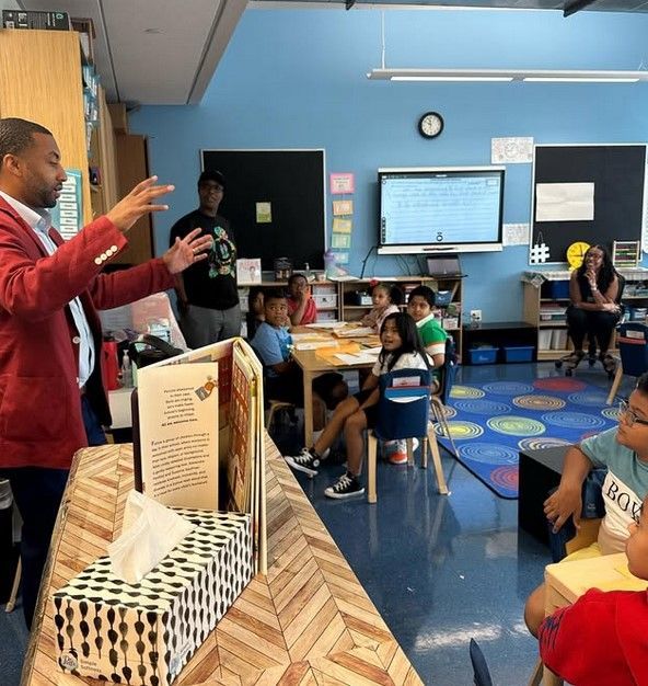 A man is giving a presentation to a group of children in a classroom
