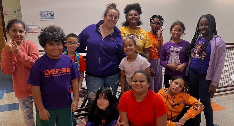 A group of children and a teacher are posing for a picture.