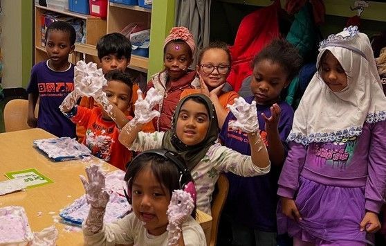 A group of children are sitting at a table with foam on their hands.