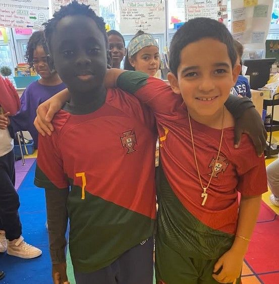 Two boys are posing for a picture and one has the number 7 on his shirt