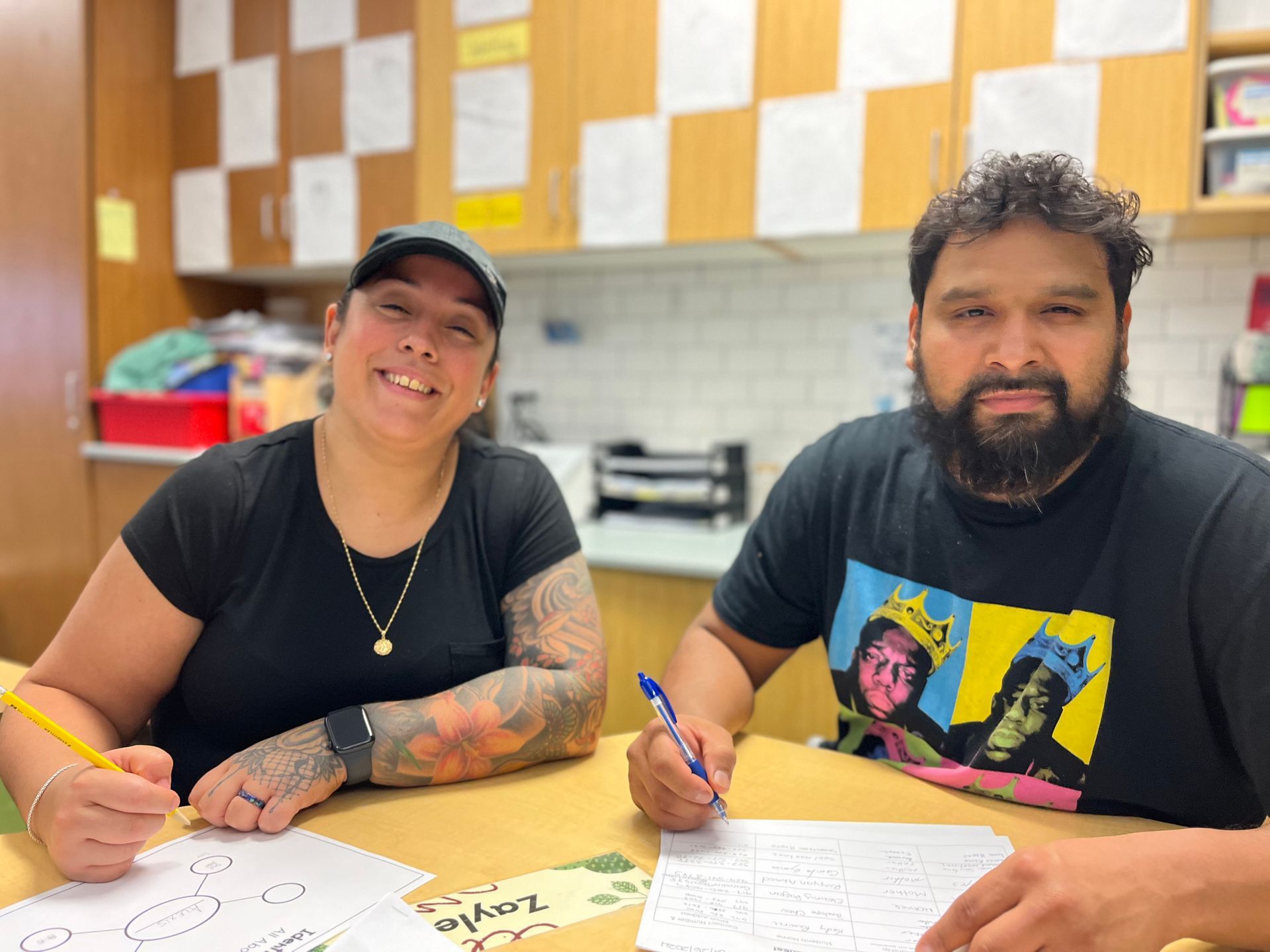 A man and a woman are sitting at a table writing