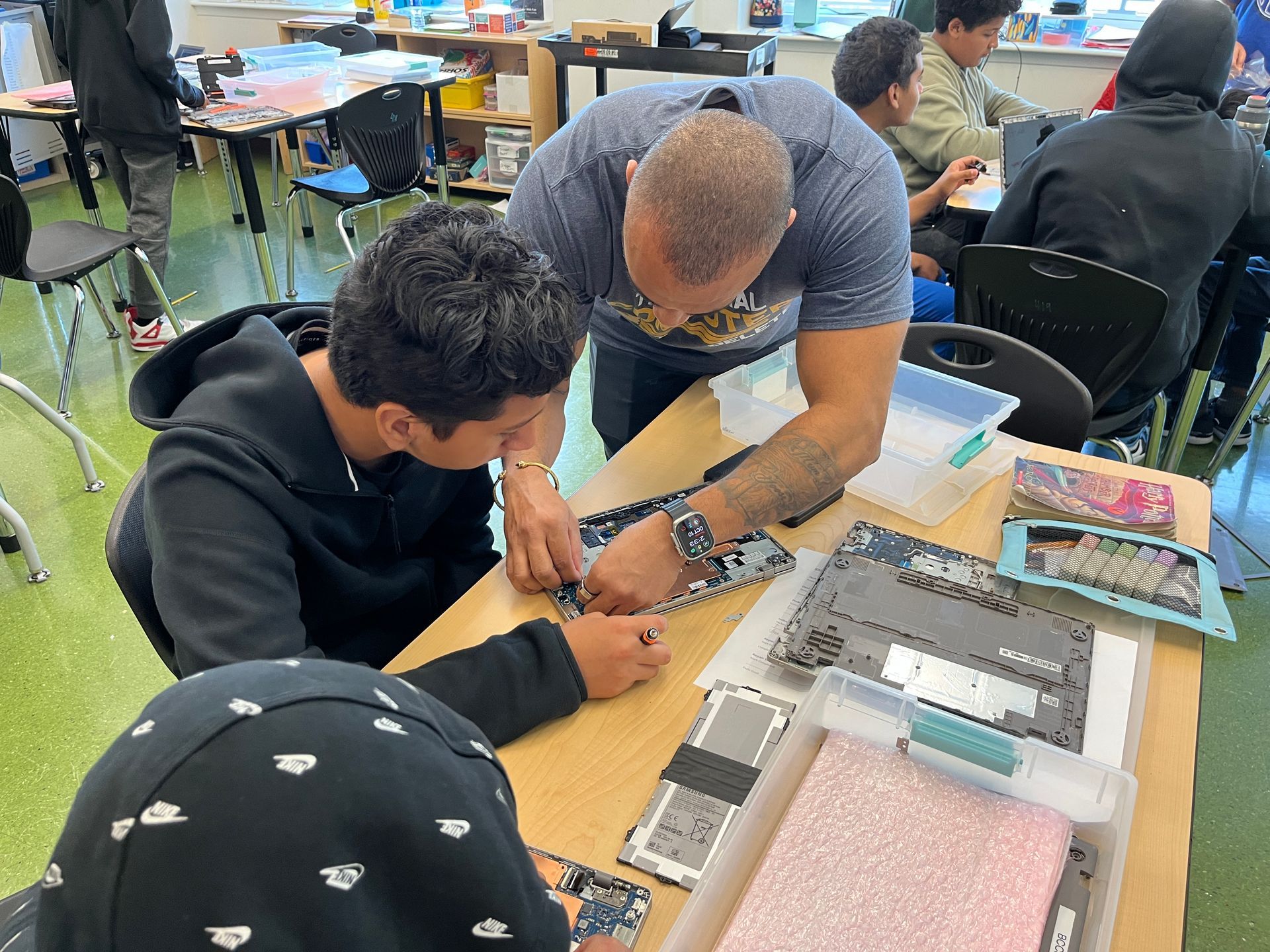 A man is helping a boy fix a cell phone