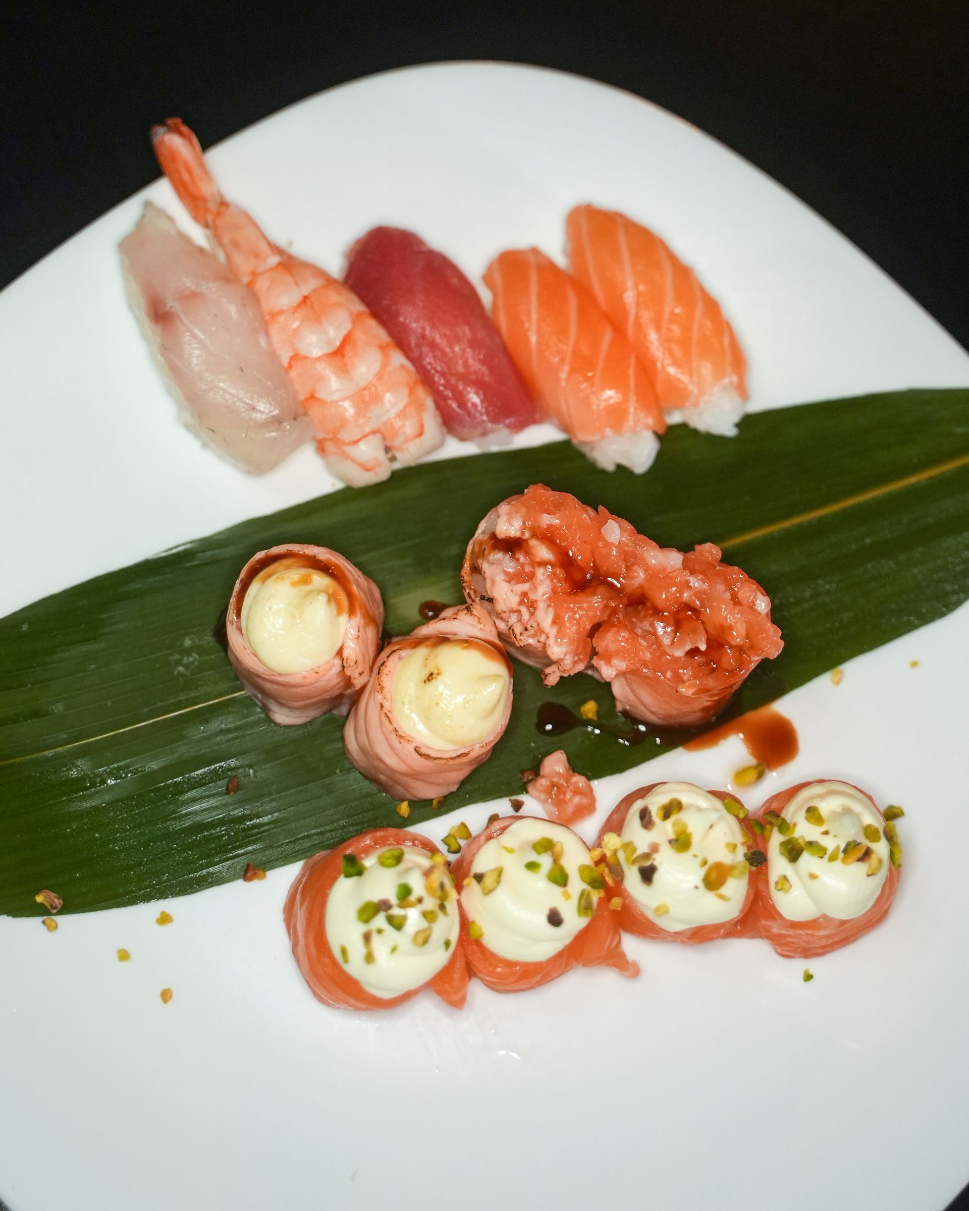 Rotolo di sushi con tempura e guarnizione sfilacciata, su un piatto bianco.