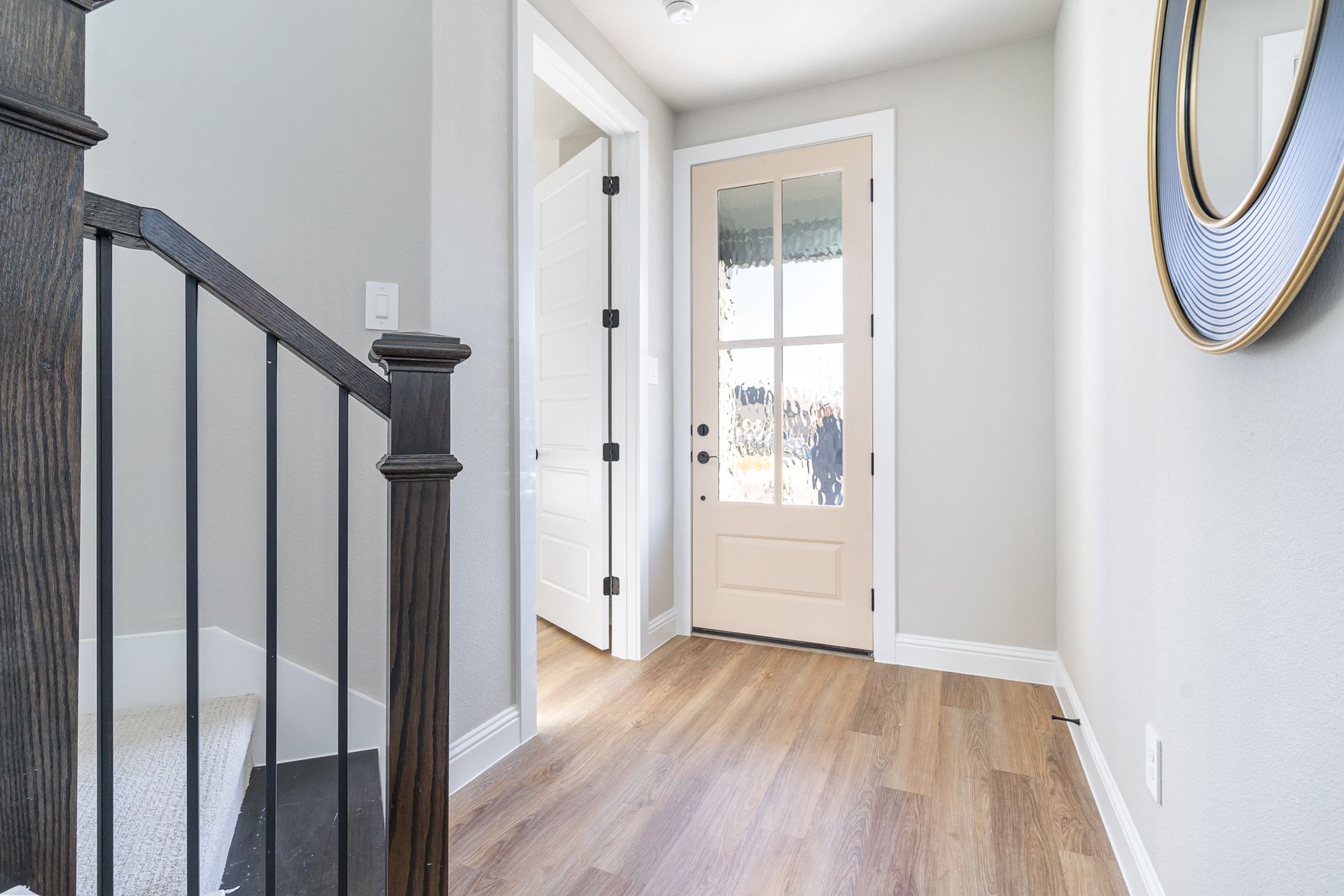 A hallway with a staircase and a door in a house.