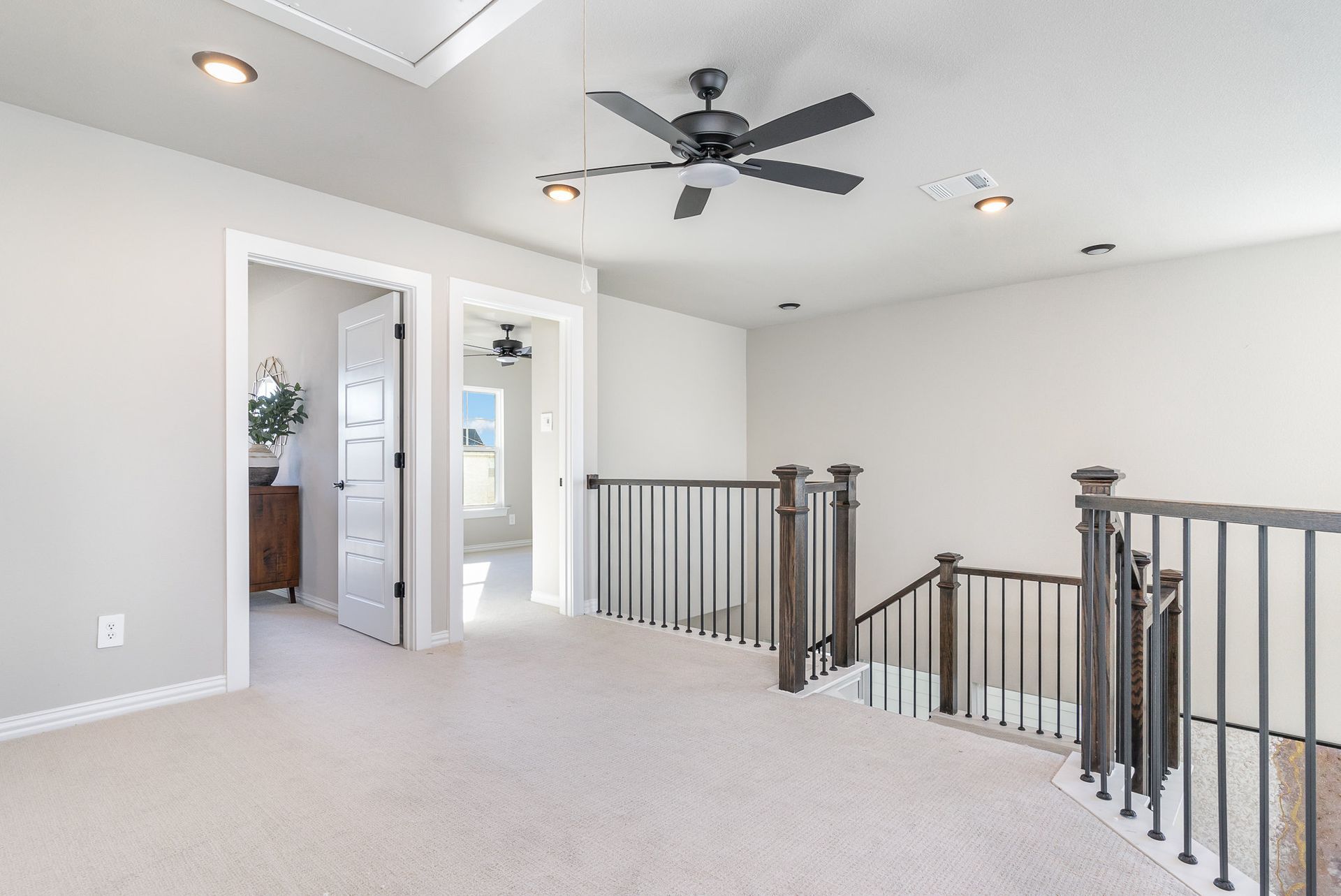 An empty room with a ceiling fan and stairs in a house.