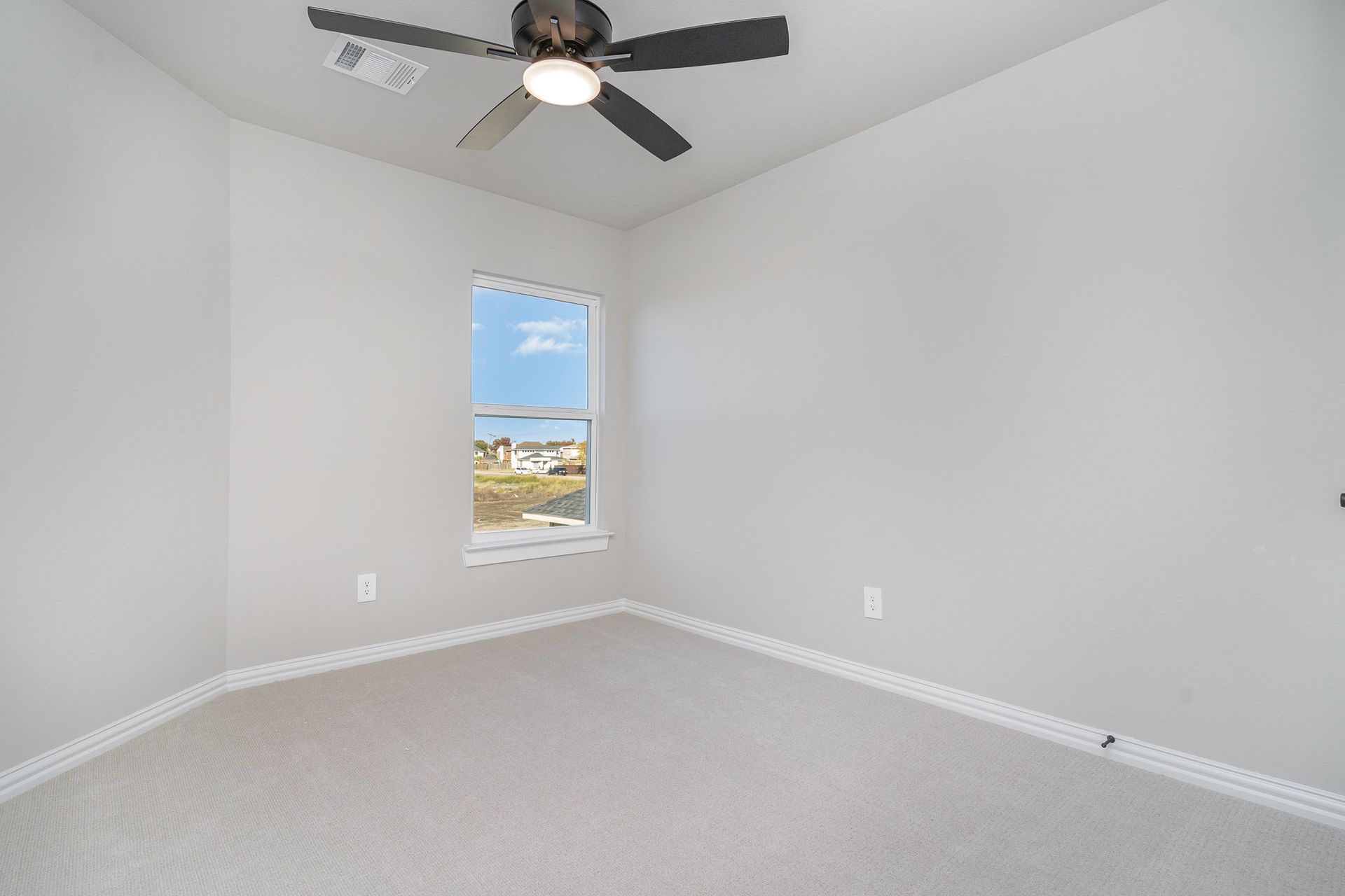 An empty bedroom with a ceiling fan and a window.