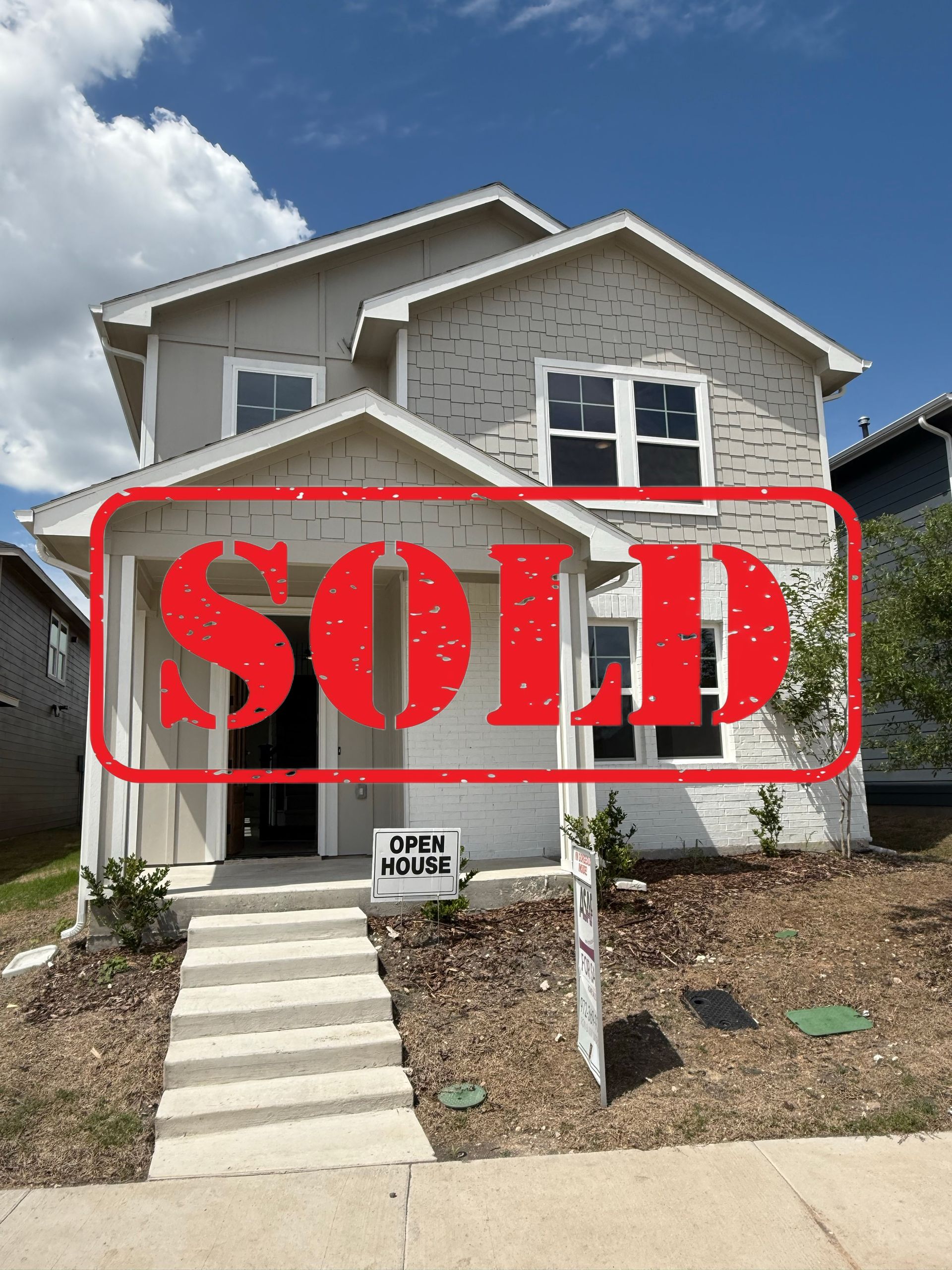 A white house with a black roof is sitting on top of a lush green field.