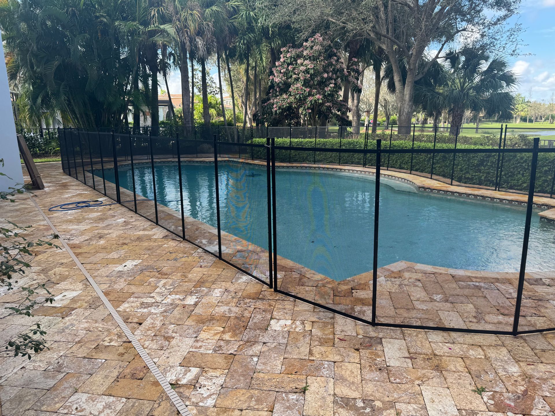 a swimming pool with a fence around it and trees in the background .