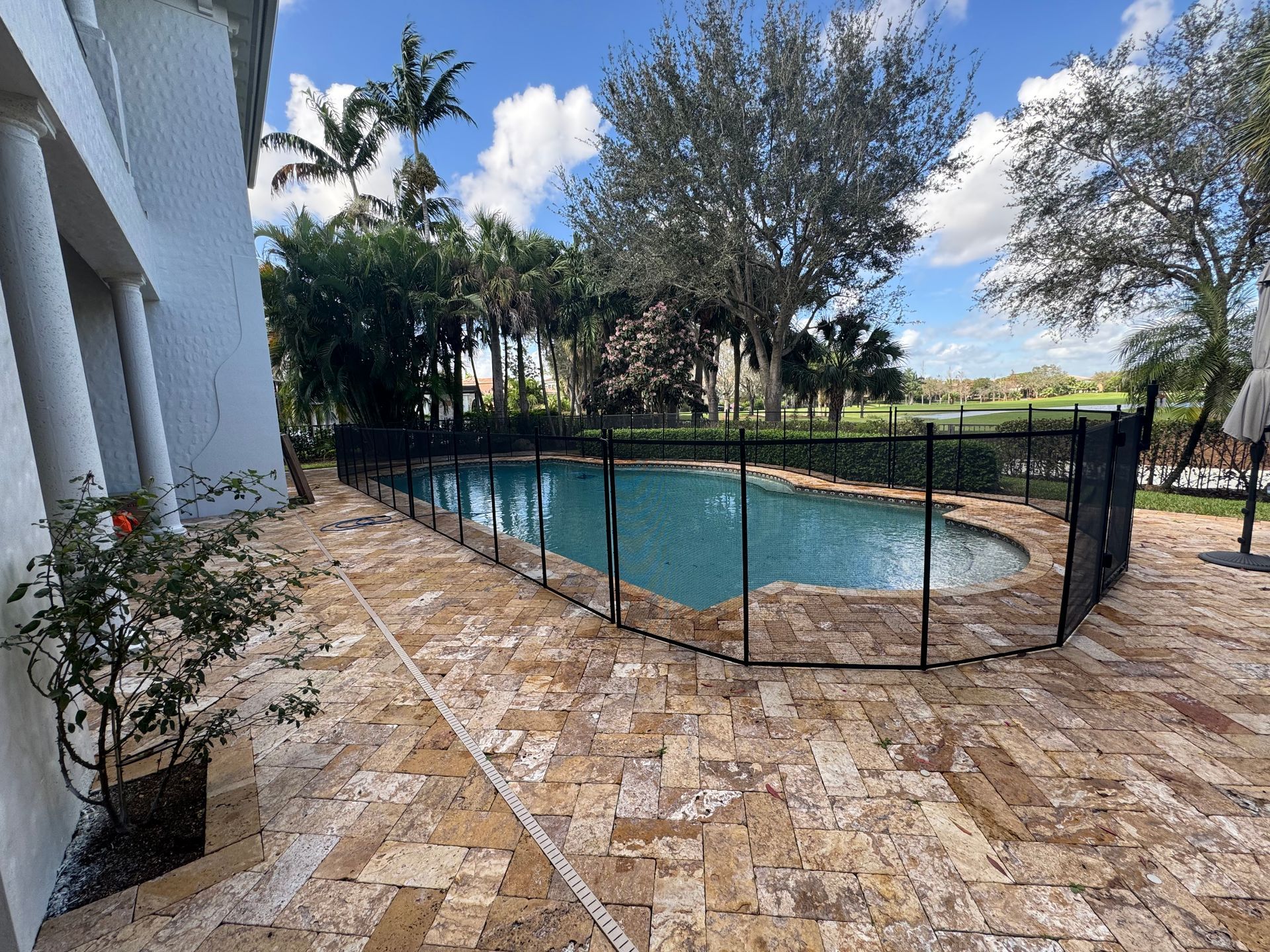 a large swimming pool surrounded by a fence and a patio .