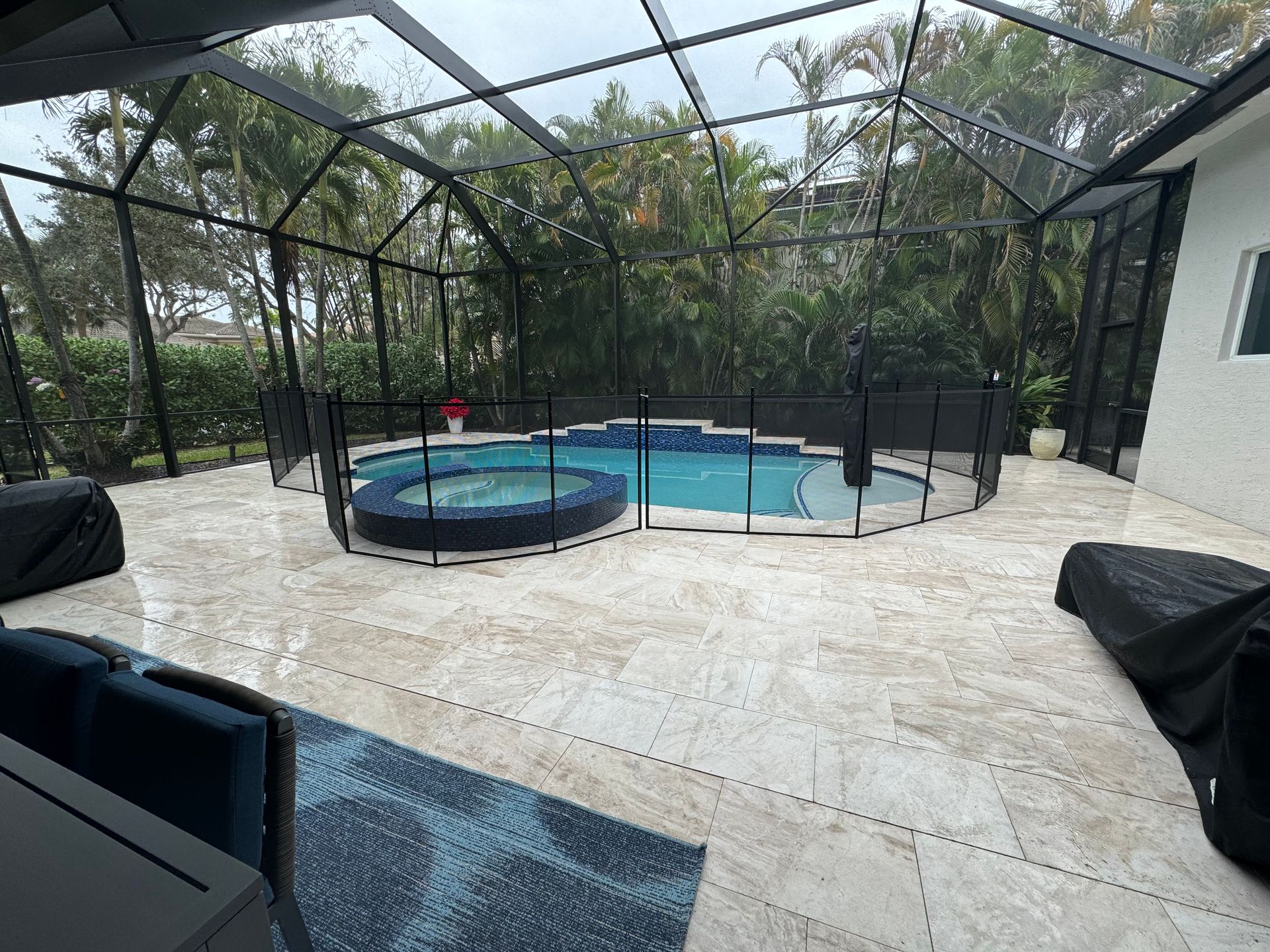 a large swimming pool with a fence around it is surrounded by a screened in area .