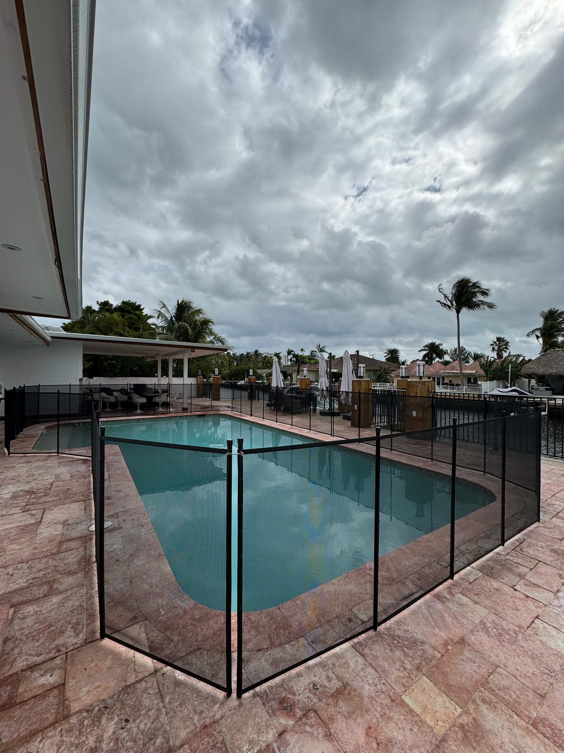 a large swimming pool surrounded by a fence on a cloudy day .