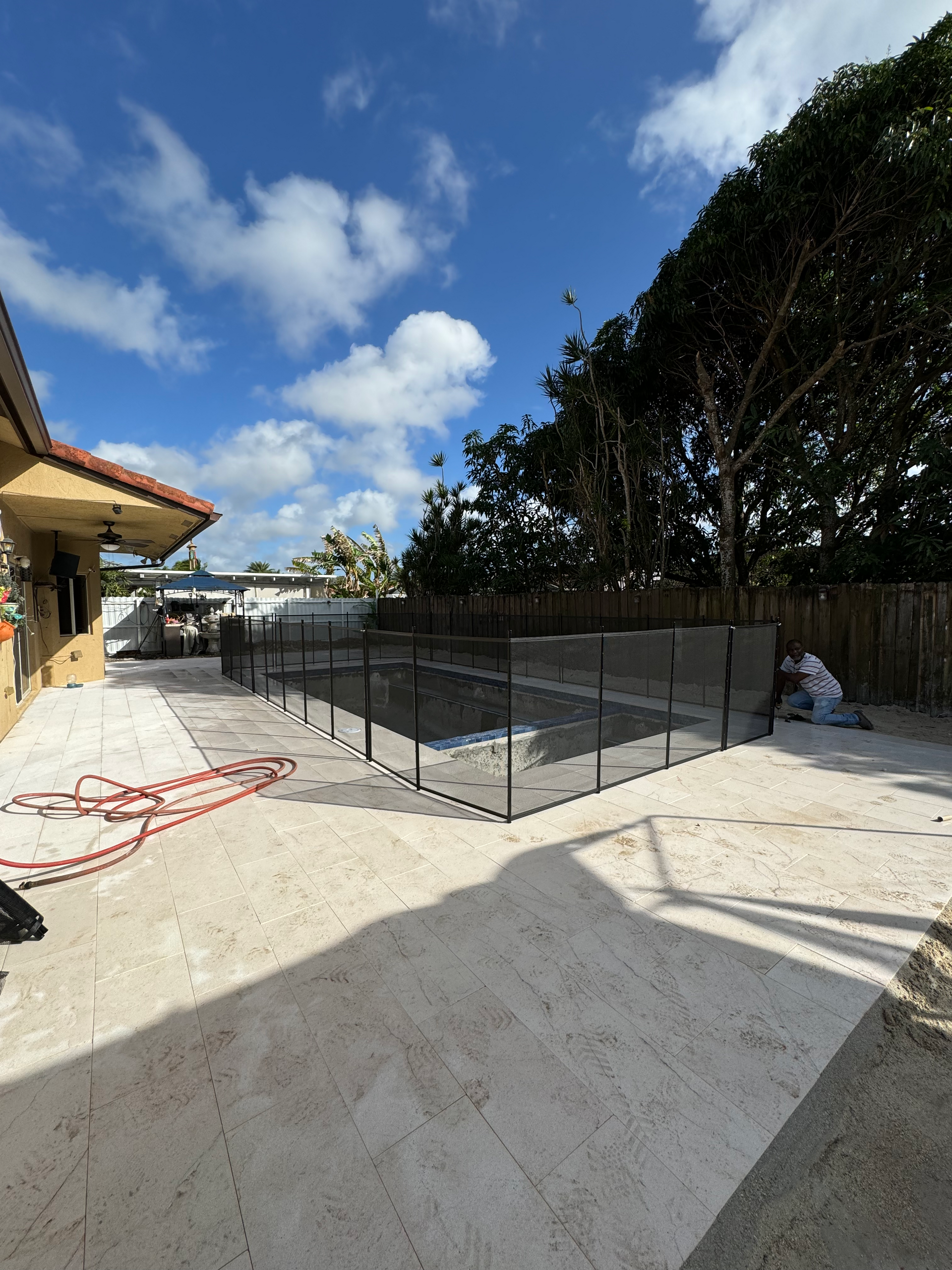 a fence surrounds a swimming pool in the backyard of a house