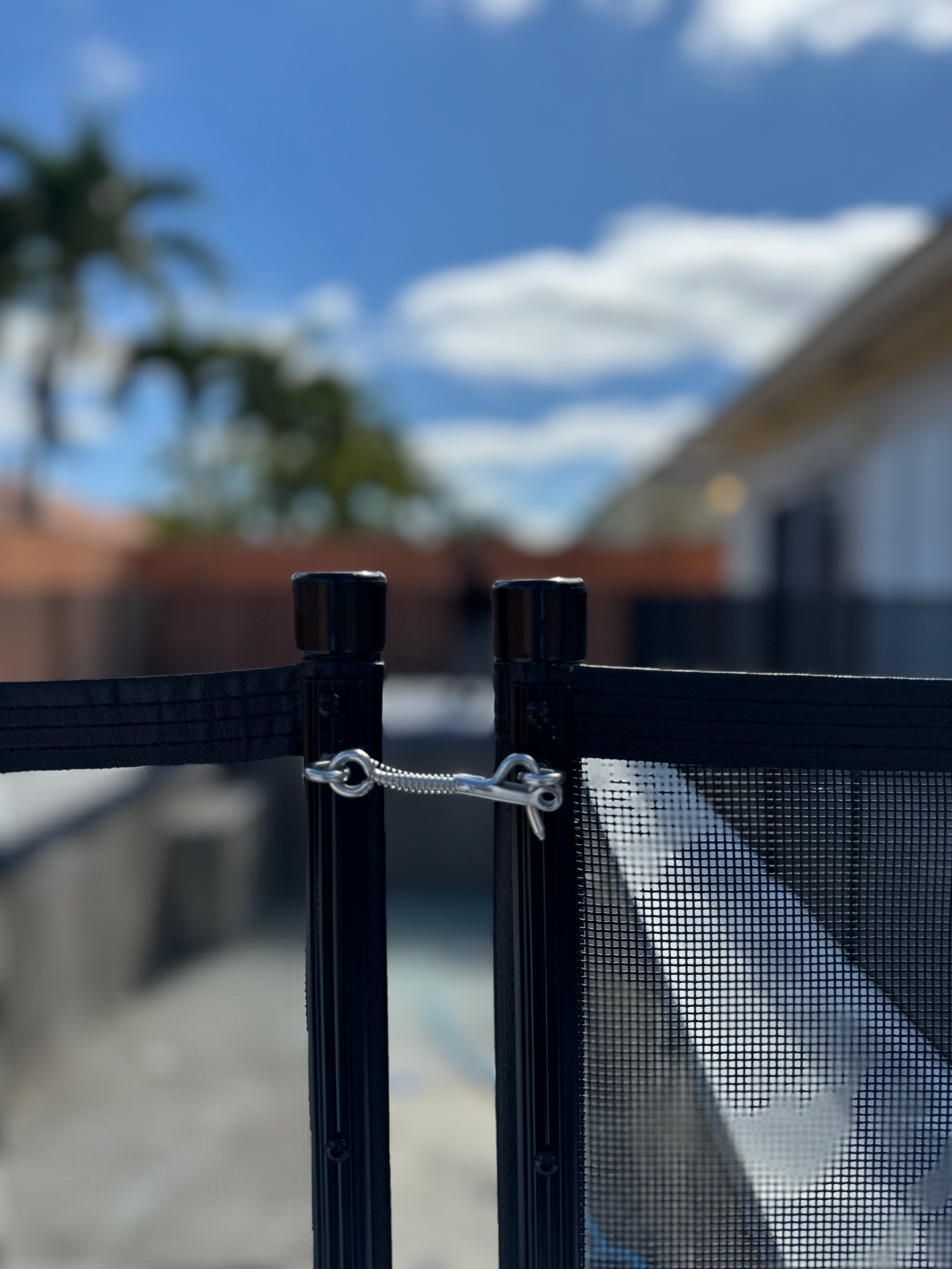 a close up of a fence with a house in the background