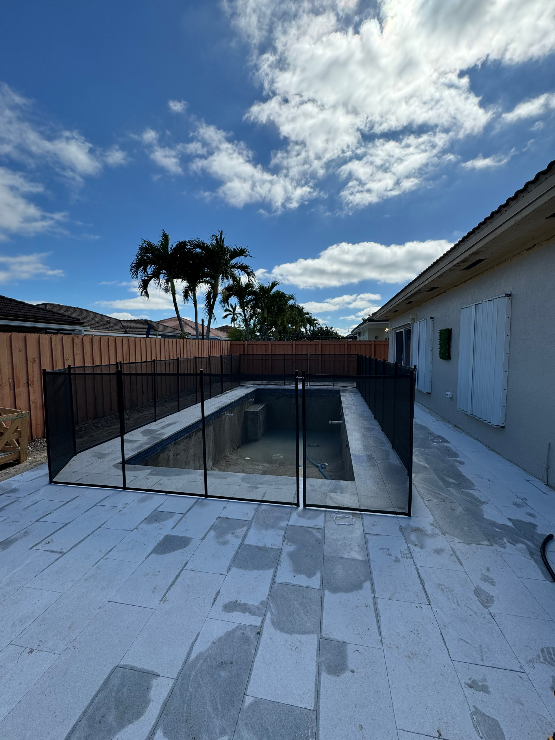 a fence around a swimming pool with palm trees in the background