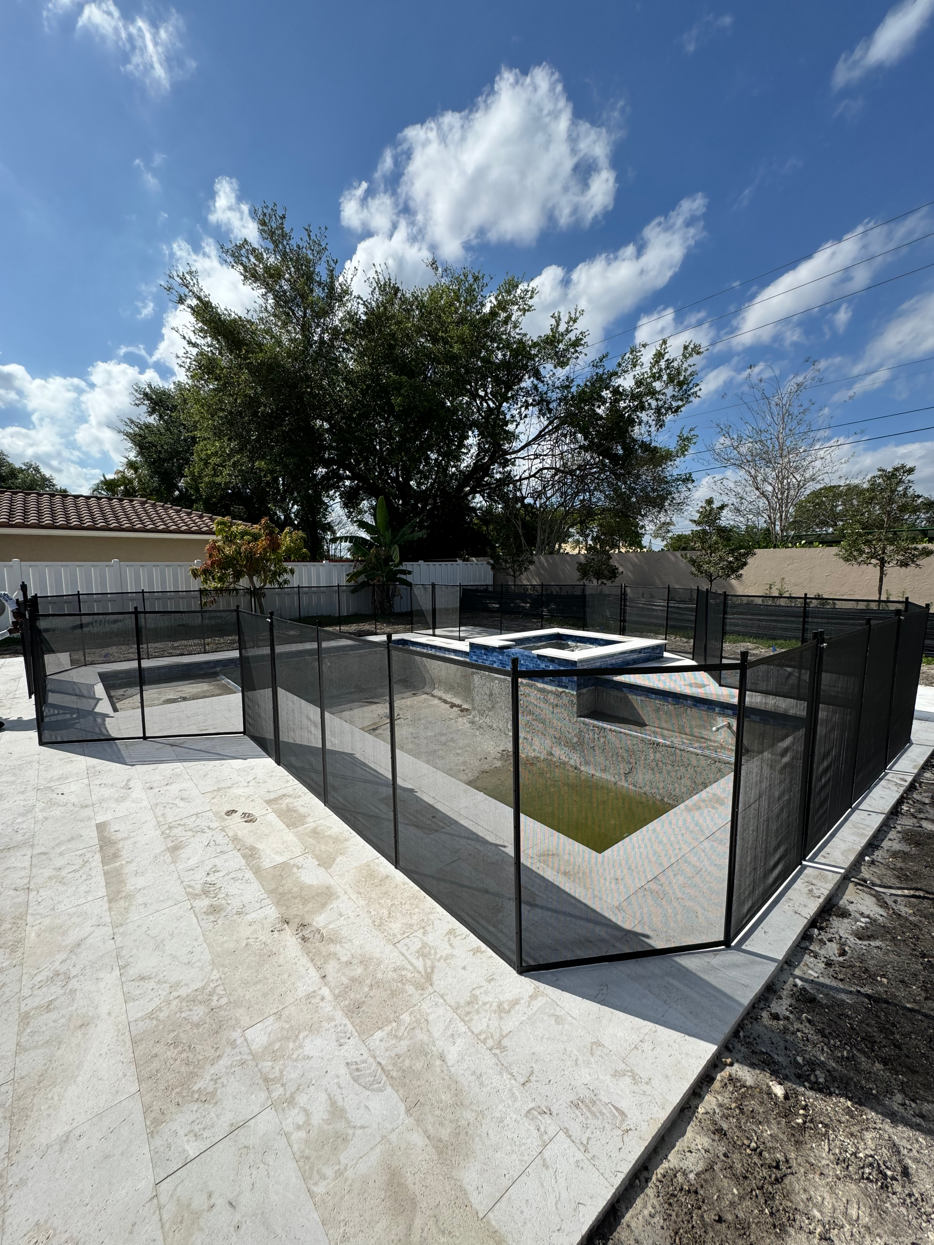 A swimming pool with a fence around it and trees in the background