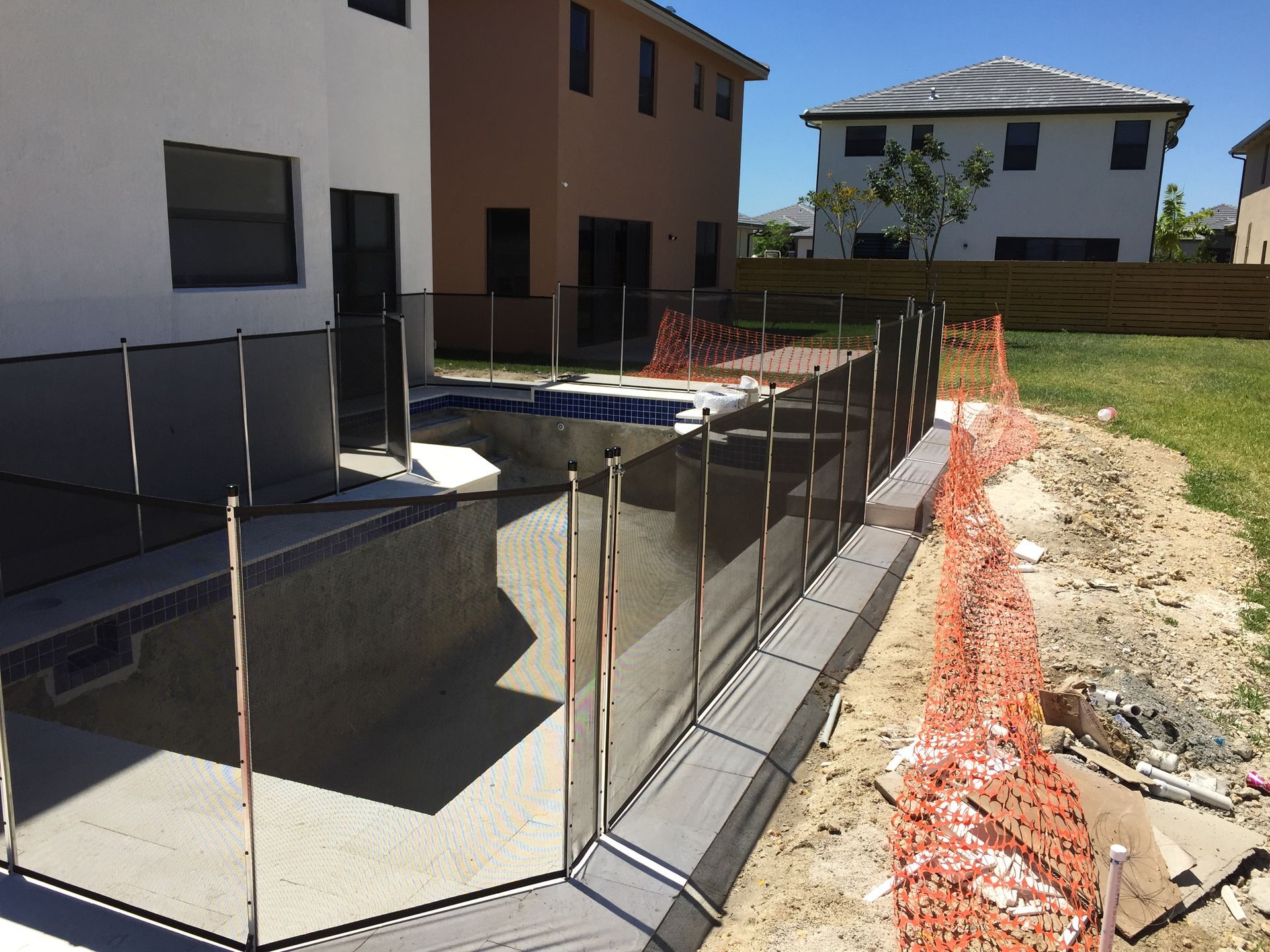 a fence around a pool with a house in the background