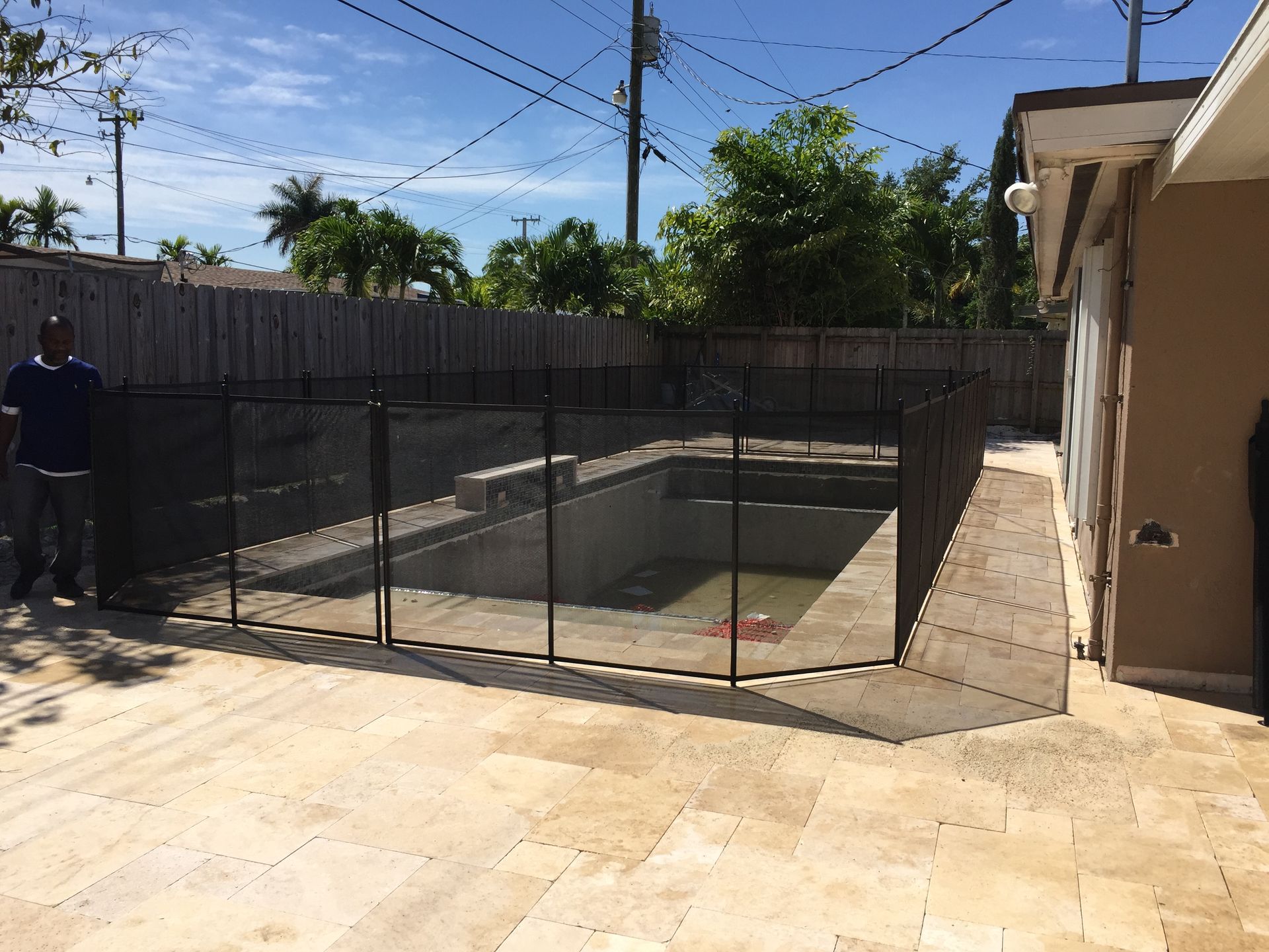 a man is standing in front of a fence around a swimming pool .