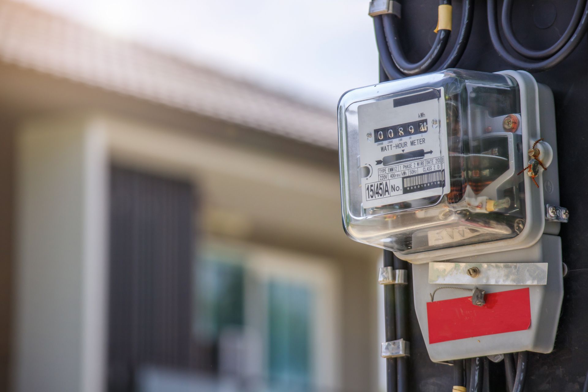 a close up of an electric meter on a pole in front of a house .