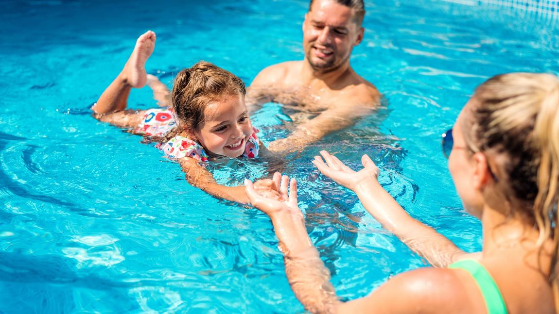 a family is playing in a swimming pool .