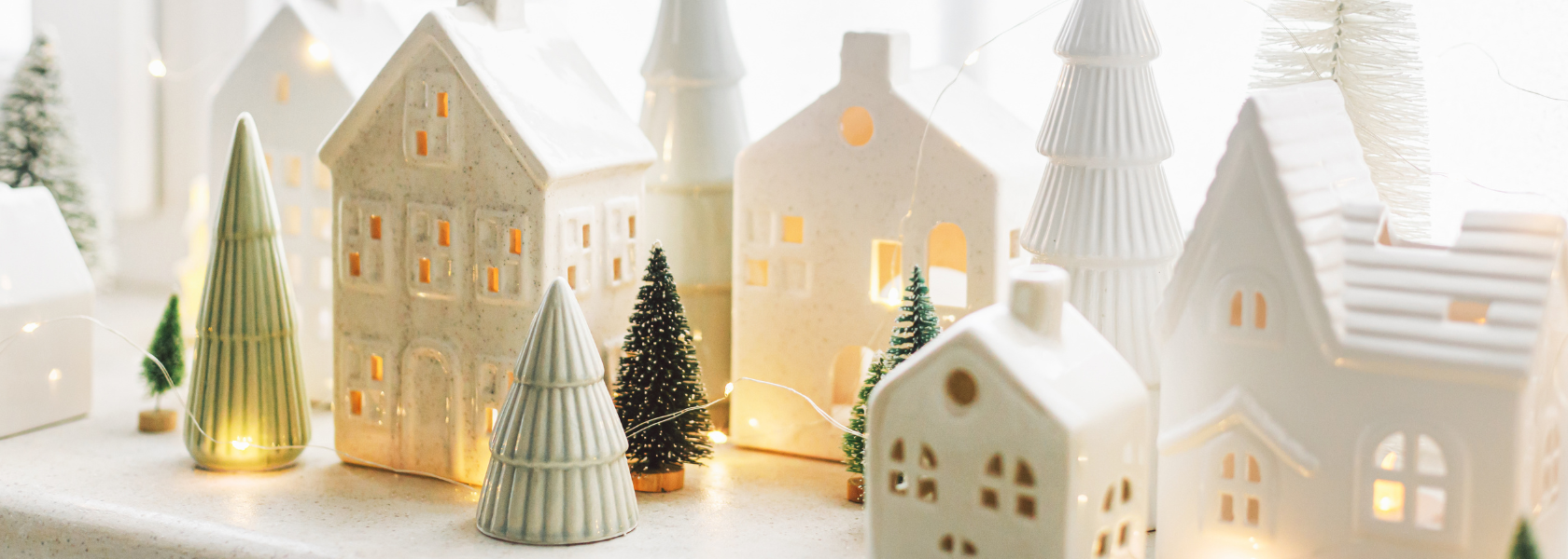 White ceramic house ornament hanging in a Christmas tree