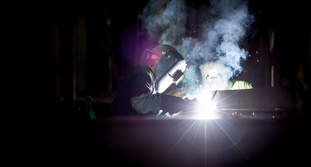 A Man is Welding a Piece of Metal in a Dark Room — Turnweld Engineering in Coolum Beach, QLD