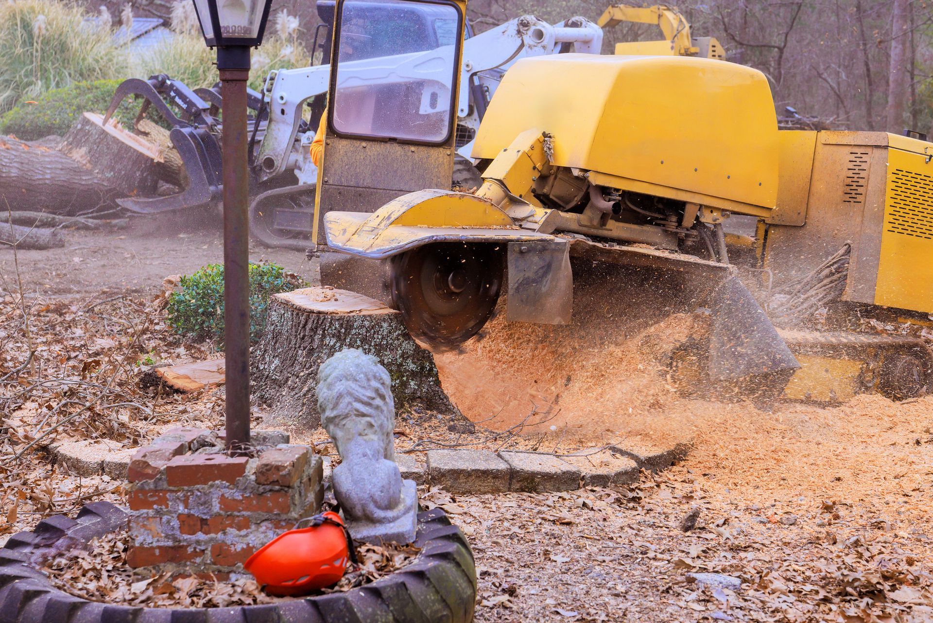 Stump grinder clears tree stump in yard with garden decor and nearby landscaping tools. Stump grinder clears tree stump in yard with garden decor and nearby landscaping tools.