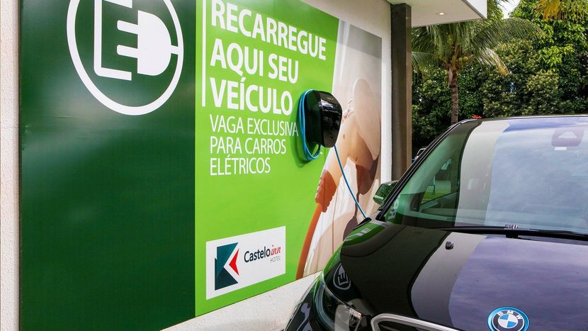 Dois carros elétricos estão sendo carregados em uma estação de carregamento.