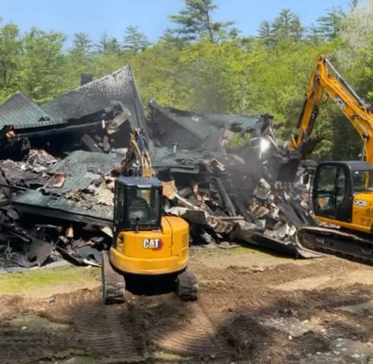 A cat excavator is demolishing a house in the woods