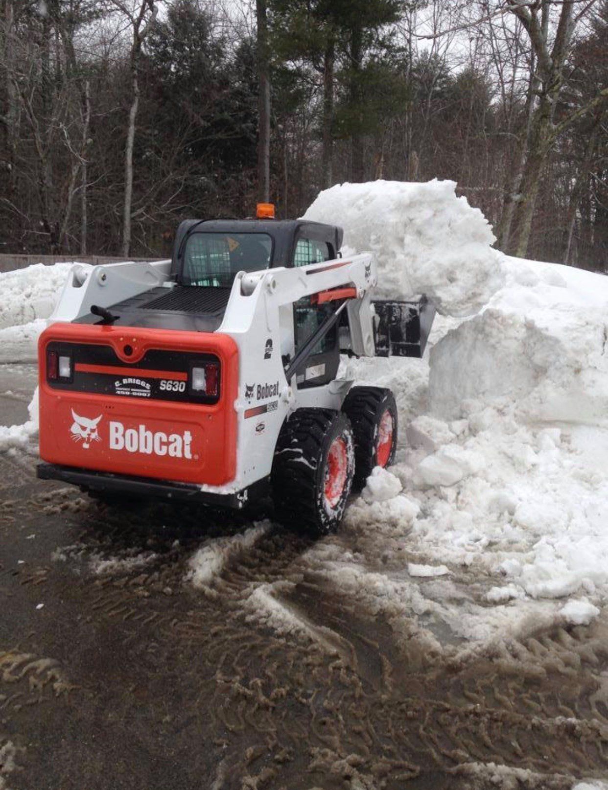 A bobcat snow plow is clearing snow from a driveway