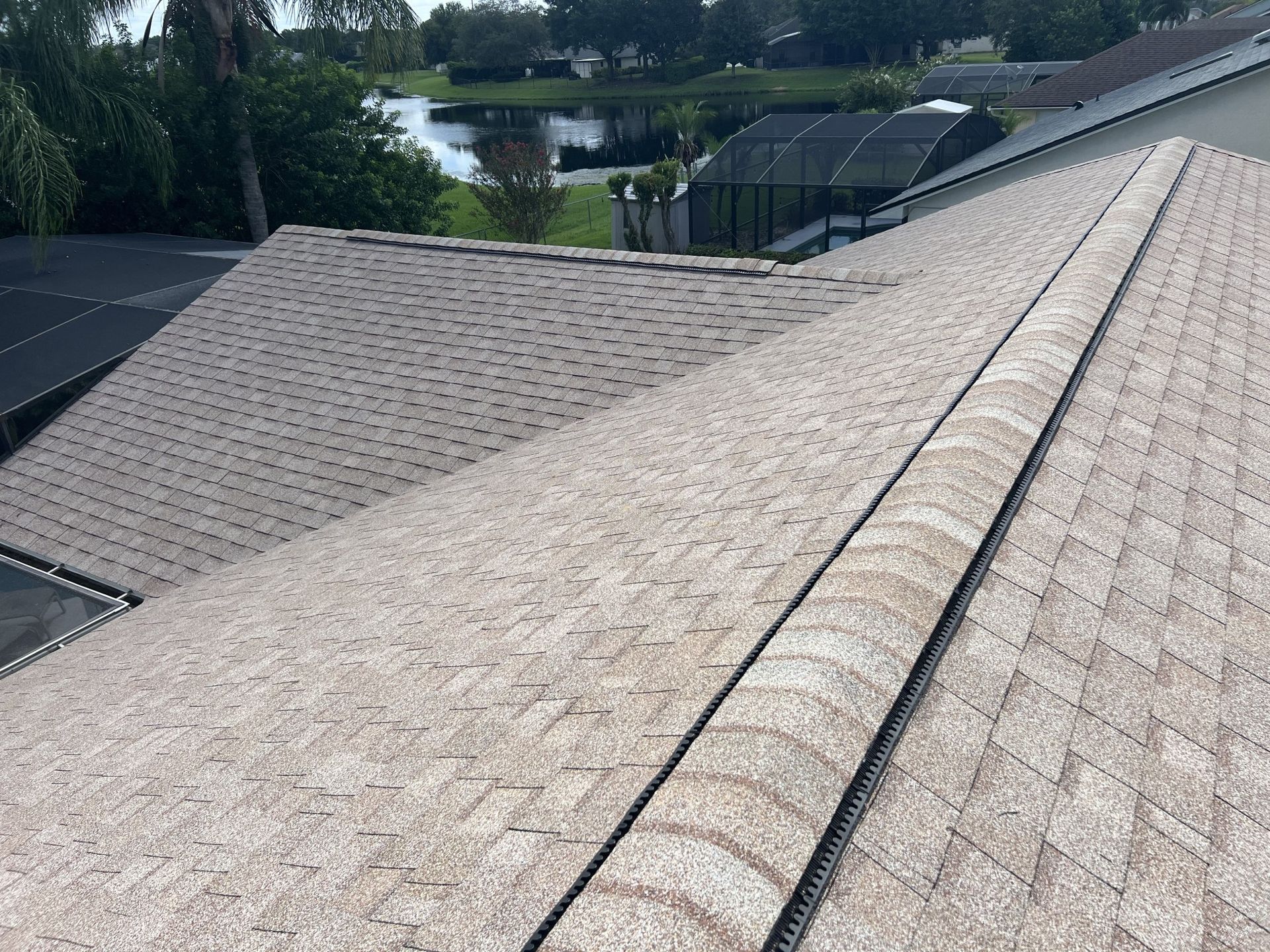 Workers repairing a rooftop with sections of orange underlayment and gray shingles