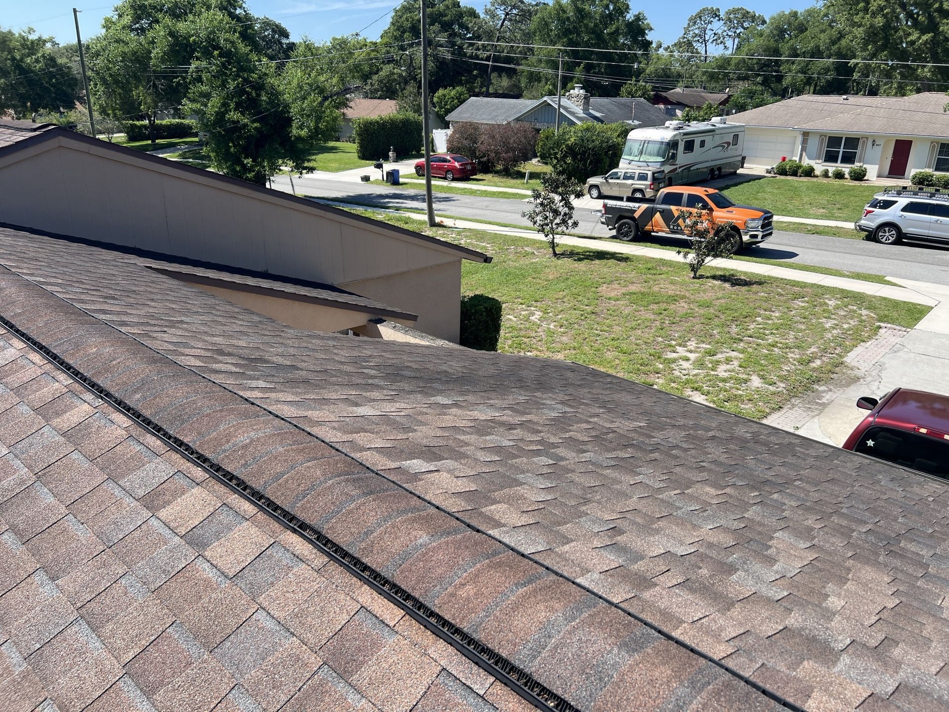 Dark gray roof tiles with solar panel mounts on a sloped roof under a blue sky