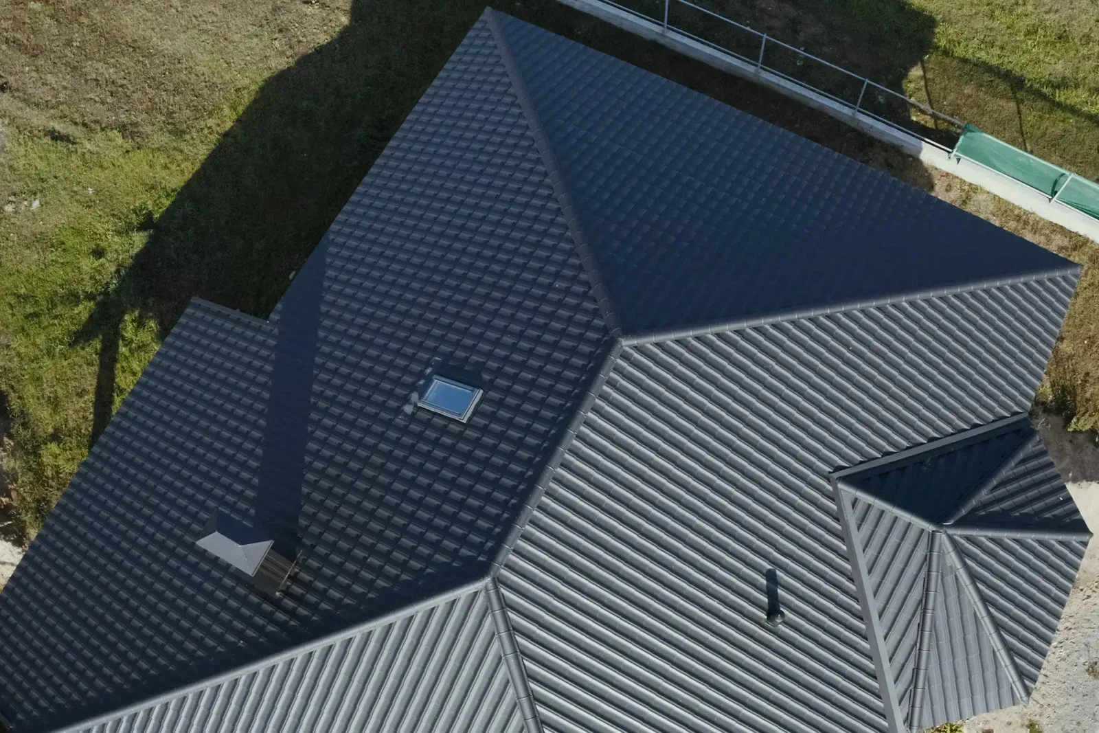 Worker installing dark roof tiles on a house roof in a suburban neighborhood